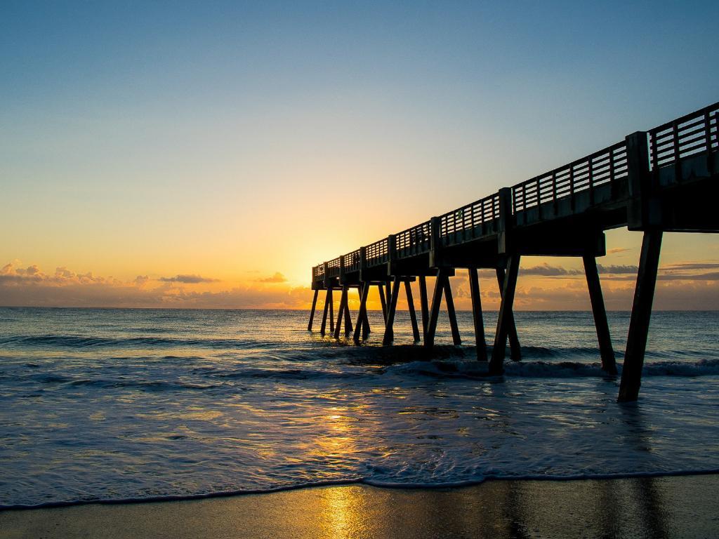 13 Romantic Beaches in Florida Offer the Perfect Couple's Getaway 5 A pier in the ocean at sunrise in Vero Beach.