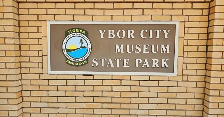 Tan brick sign at Ybor City Museum State Park has the state parks emblem and reads "Ybor City Museum State Park".